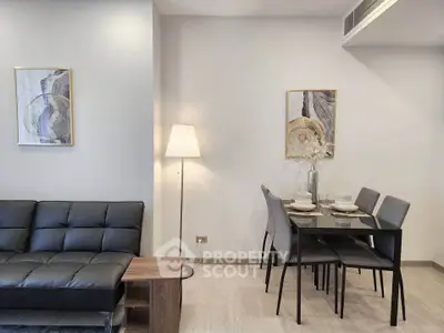 Modern living room with sleek black sofa and elegant dining area, perfect for stylish urban living.