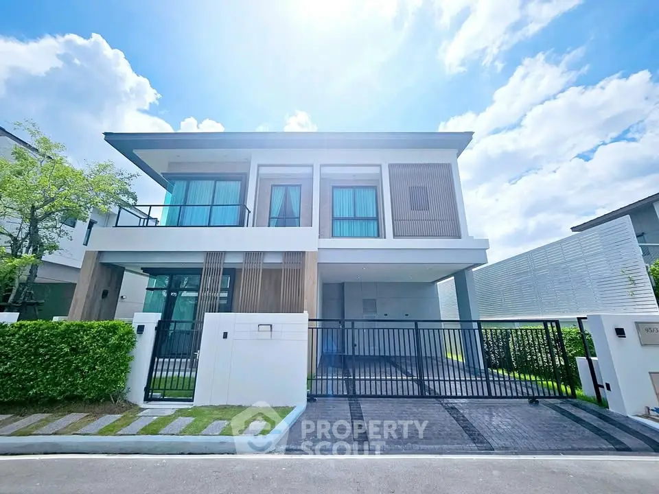 Modern two-story house with sleek design and spacious driveway under a bright blue sky.