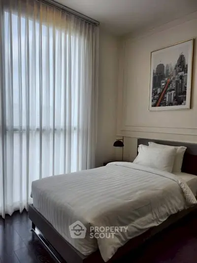 Modern bedroom with single bed and floor-to-ceiling window with sheer curtains.