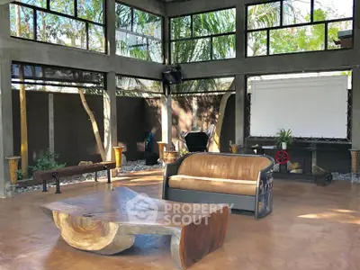 Spacious modern living area with large windows and unique wooden furniture, perfect for relaxation and entertainment.