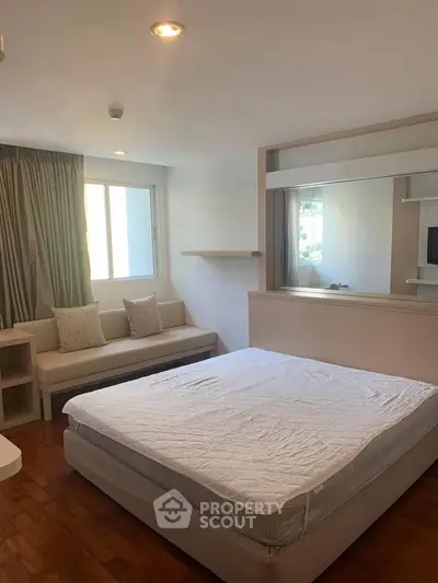 Spacious bedroom with natural light and cozy seating area, perfect for relaxation.