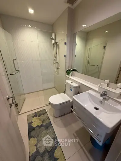 Modern bathroom with glass shower, sleek fixtures, and stylish decor in a contemporary apartment.