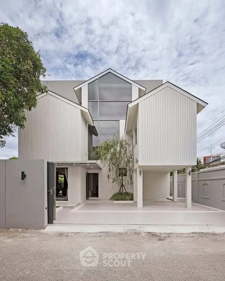 Modern minimalist white house exterior with unique architectural design and large windows.