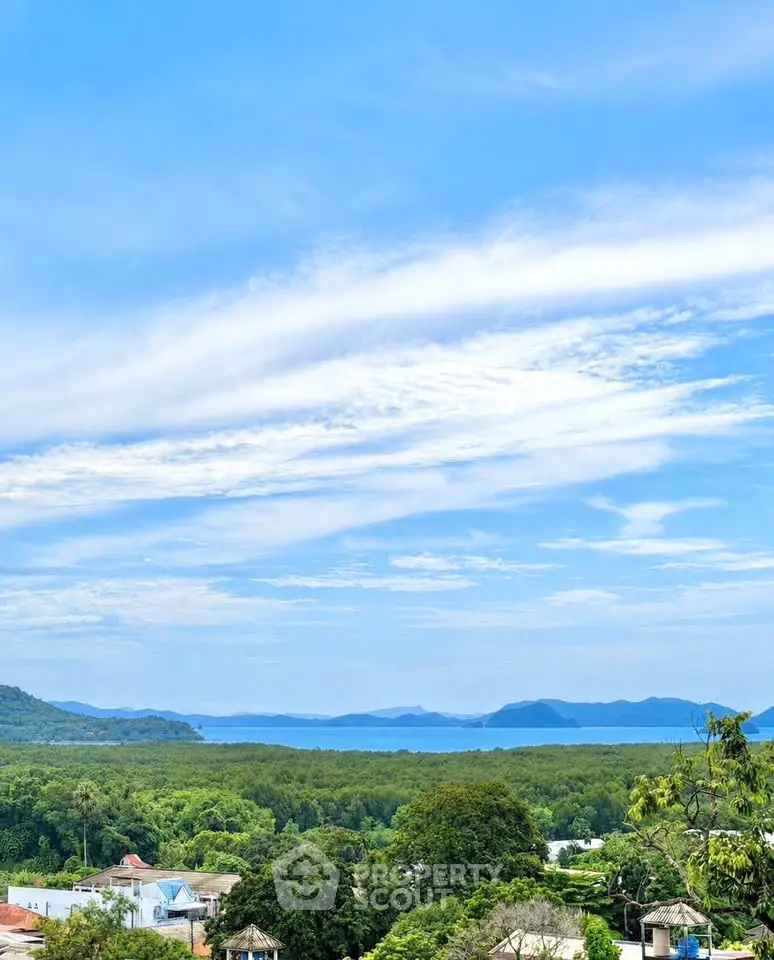 Stunning panoramic view of lush greenery and ocean from a high vantage point, perfect for serene living.