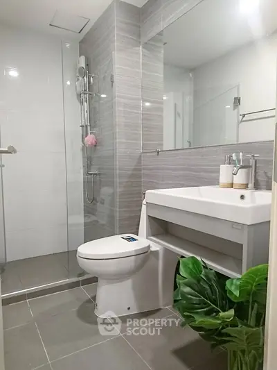 Modern bathroom with sleek fixtures and glass shower enclosure in contemporary apartment.