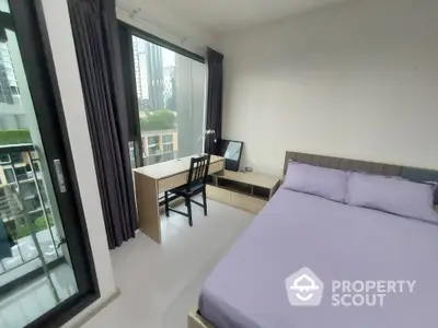 Modern bedroom with city view and workspace near balcony in high-rise apartment.