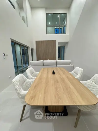 Spacious modern dining area with high ceilings and elegant furniture in a contemporary home.