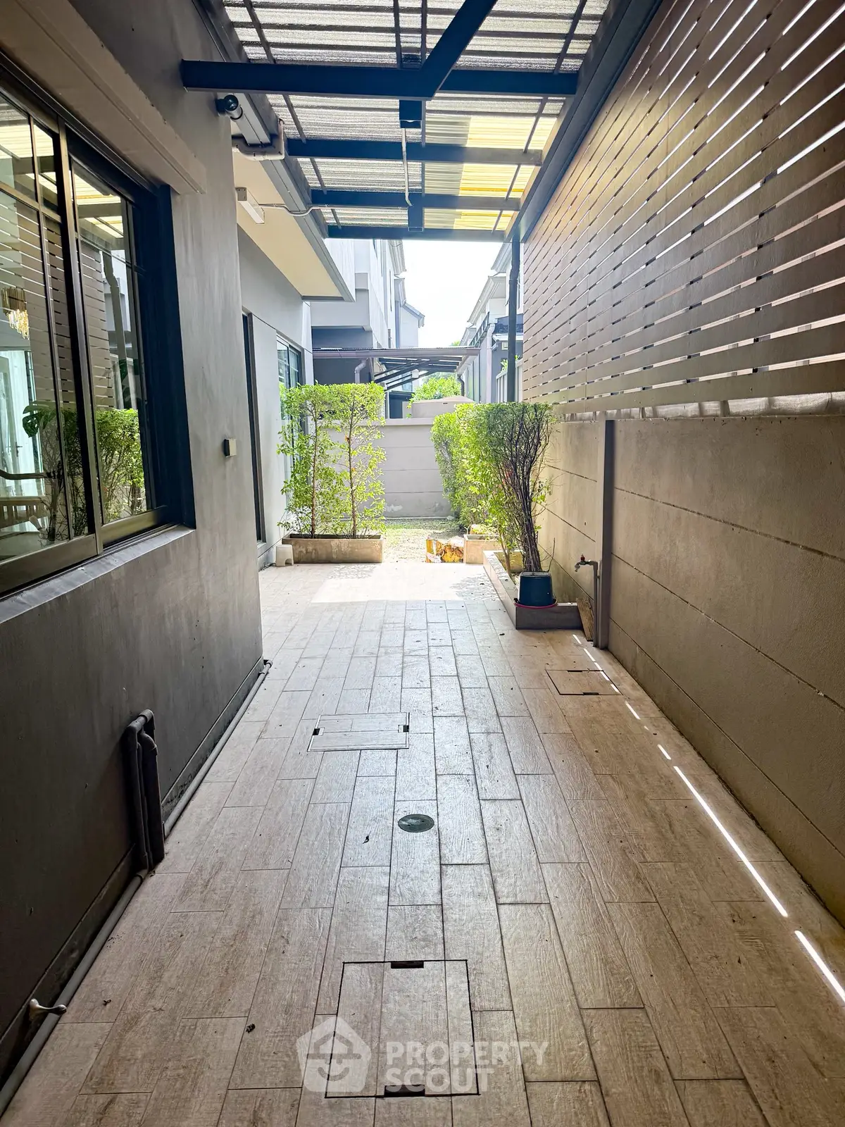 Modern outdoor corridor with wooden flooring and greenery in a contemporary home