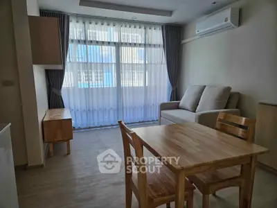 Modern living room with natural light, featuring wooden furniture and a cozy sofa, ideal for relaxation.
