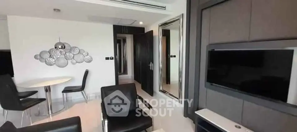 Modern living room with sleek black furniture and wall-mounted TV in a stylish apartment.