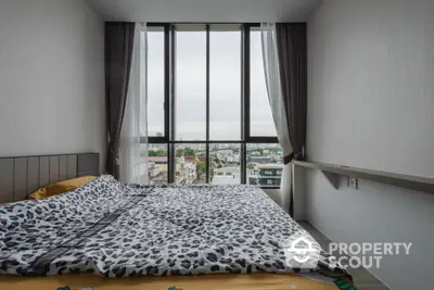 Modern bedroom with large window offering stunning city view and stylish decor.