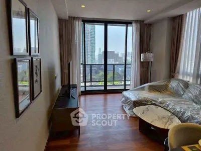 Modern living room with large windows and city view, featuring stylish furniture and hardwood floors.