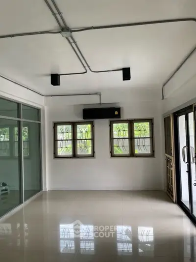 Spacious living room with large windows and modern lighting, perfect for natural light and comfort.
