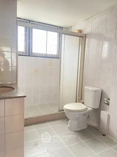 Spacious bathroom with shower and modern fixtures in a bright real estate property.