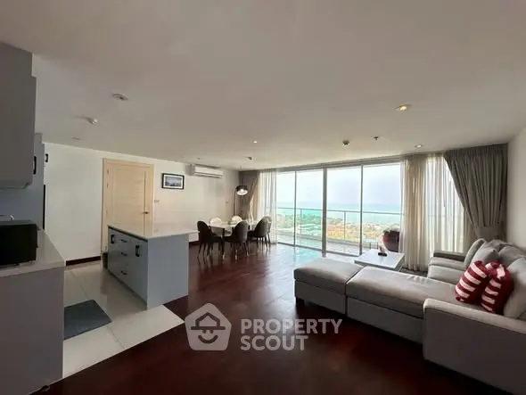 Spacious living room with ocean view, modern furniture, and open layout in luxury apartment.