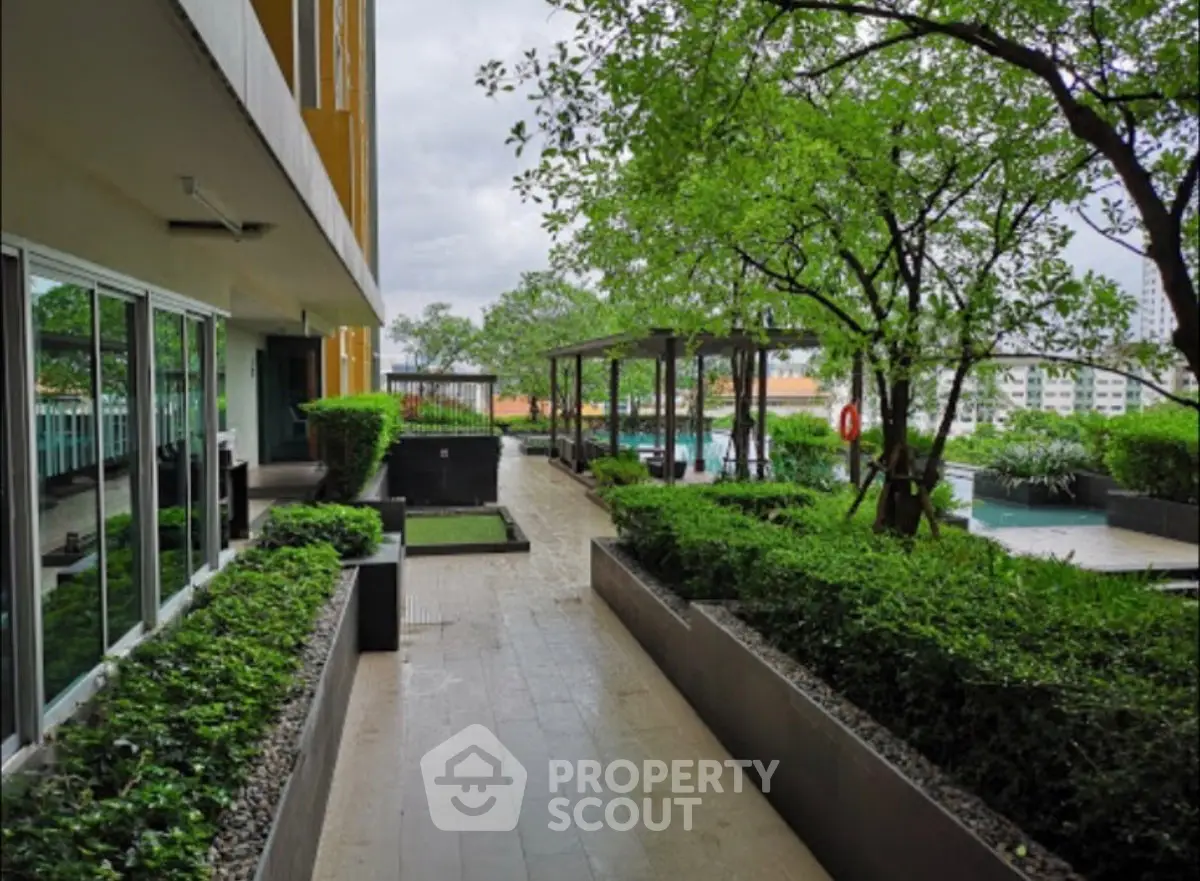 Luxurious apartment building with lush garden and poolside view, perfect for relaxation and leisure.
