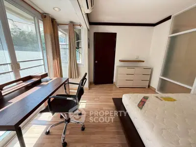 Bright bedroom with study area, large windows, and modern furnishings in a stylish apartment.