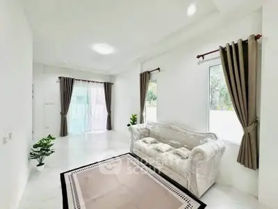 Spacious living room with elegant sofa and large windows offering natural light.