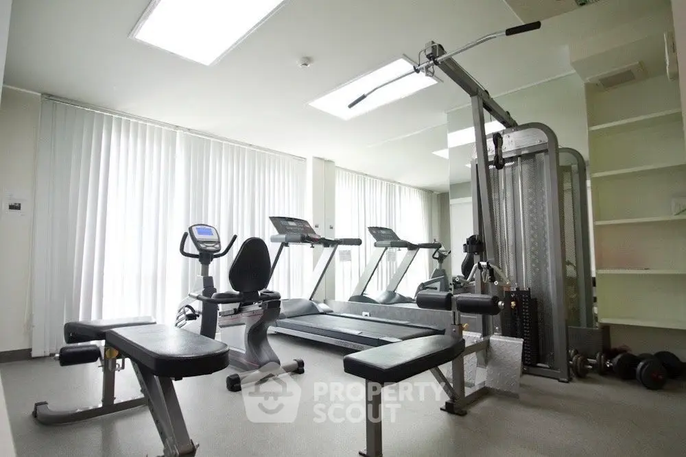 Modern gym with state-of-the-art equipment and natural lighting in luxury apartment complex.