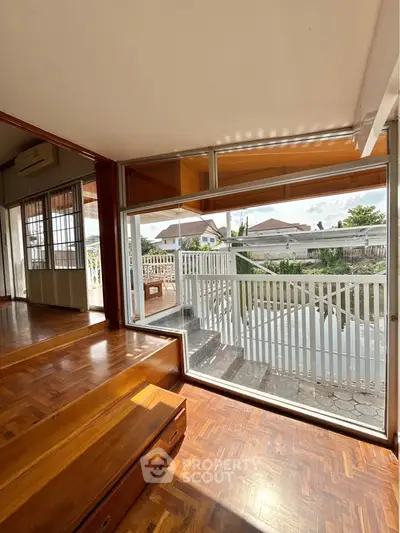 Spacious living area with large windows overlooking a serene water view, featuring elegant wooden flooring.