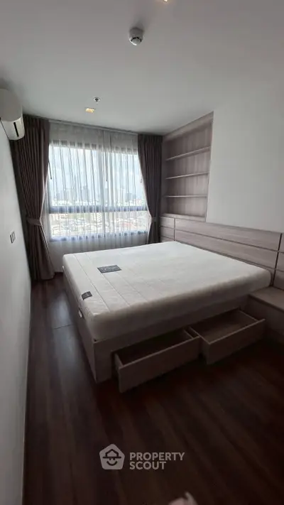 Spacious bedroom with large window and built-in storage in modern apartment.