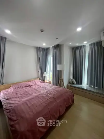 Spacious bedroom with modern decor and large windows for natural light.