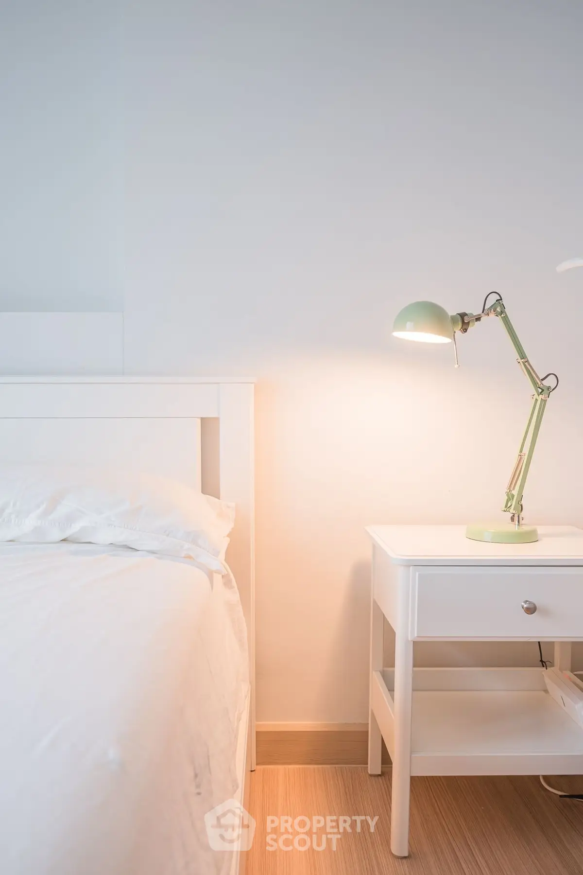 Cozy bedroom with white furniture and stylish lamp, perfect for a serene retreat.