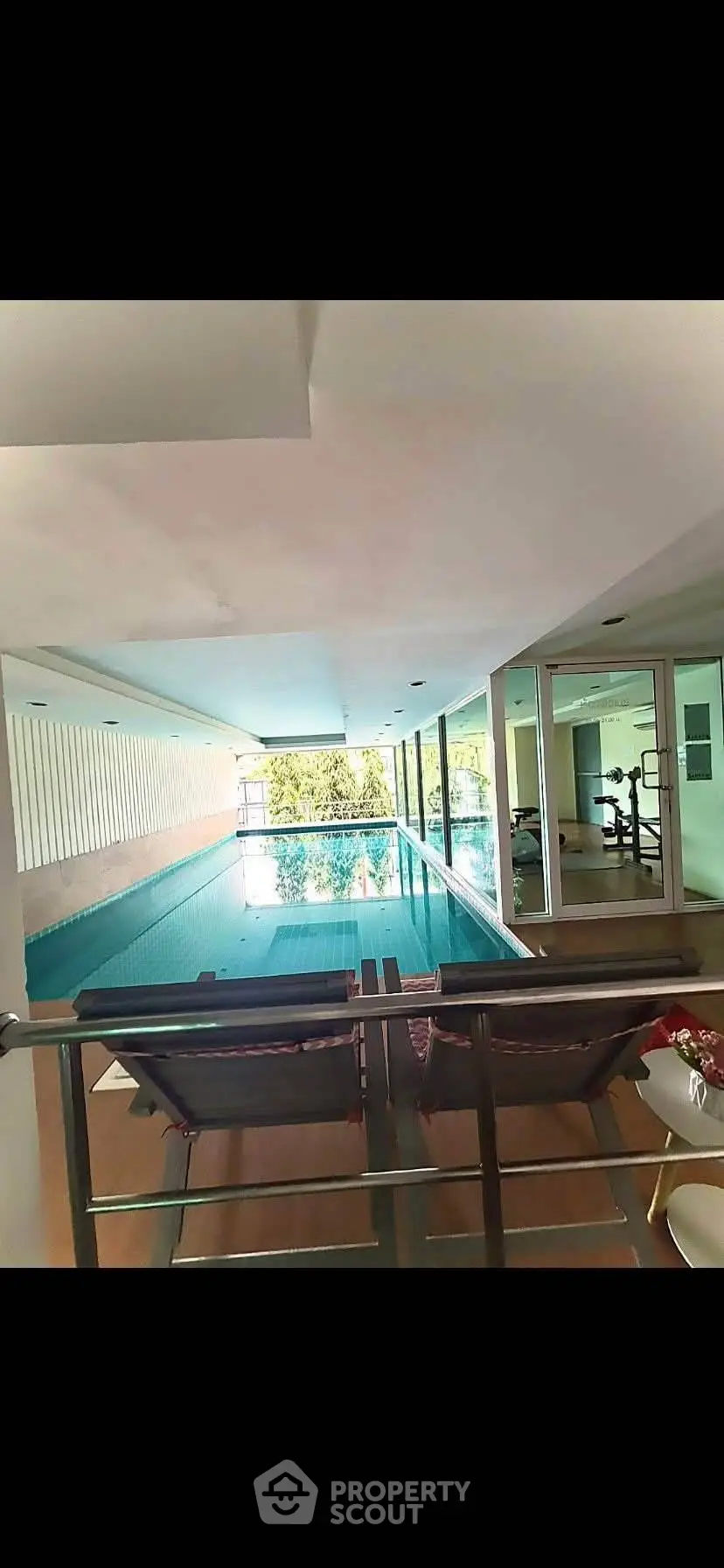 Luxurious indoor pool with modern gym facilities and relaxing lounge chairs.