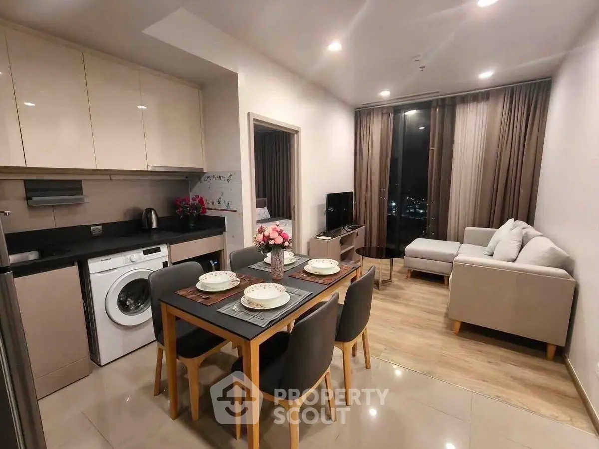 Modern open-plan living room and kitchen with elegant dining area and cozy seating.
