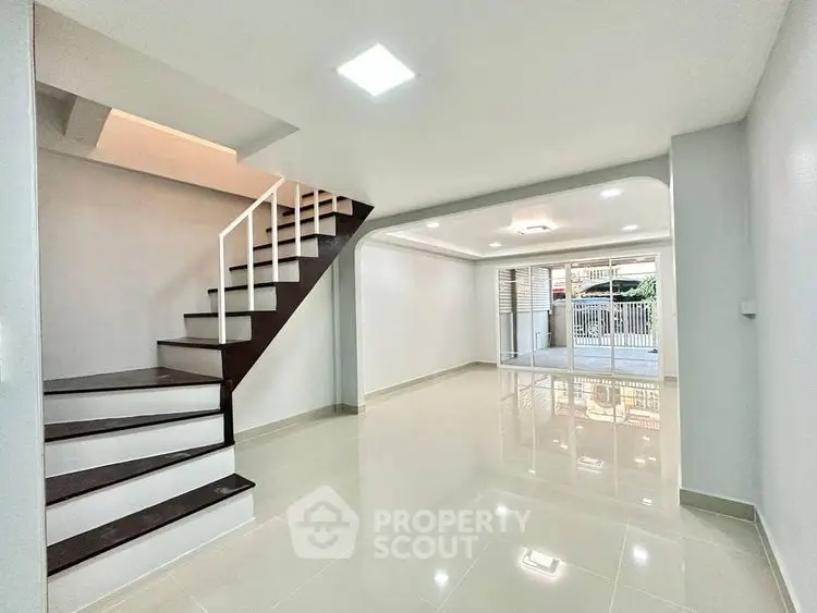 Spacious modern living room with sleek staircase and large windows