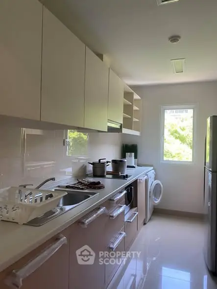 Modern kitchen with sleek cabinets, appliances, and natural light from window.