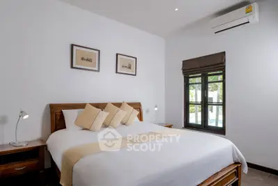 Spacious bedroom with elegant decor and natural light, featuring a comfortable bed and modern air conditioning.