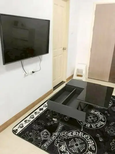 Modern living room with wall-mounted TV and stylish black coffee table on designer rug.