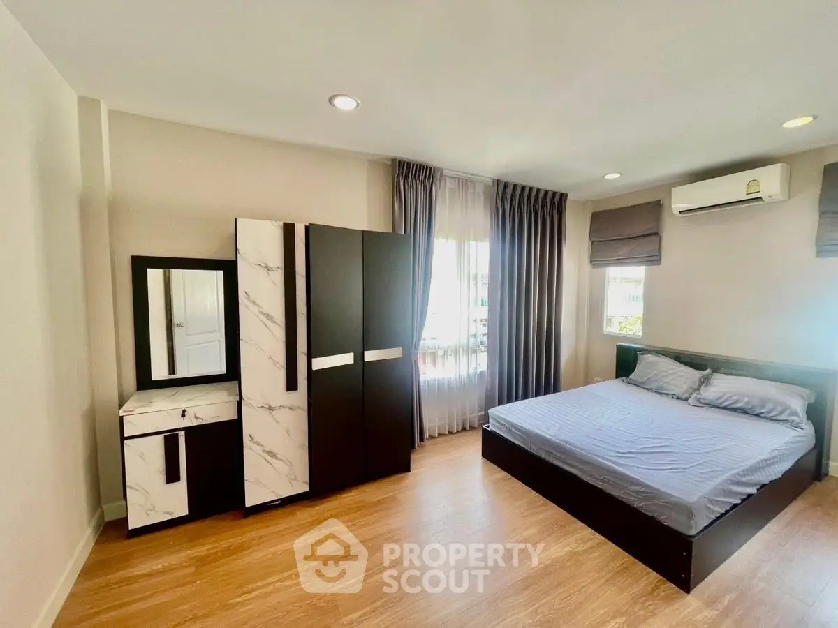 Spacious bedroom with modern furniture and natural light, perfect for comfortable living.