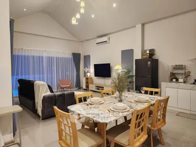 Spacious modern living room with dining area and high ceiling, featuring elegant decor and ample natural light.