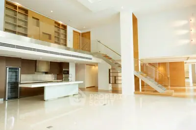 Luxurious modern living room with open kitchen and elegant staircase in a spacious apartment.