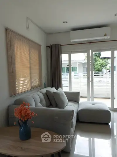 Cozy living room with modern sofa, large windows, and air conditioning, perfect for relaxation.