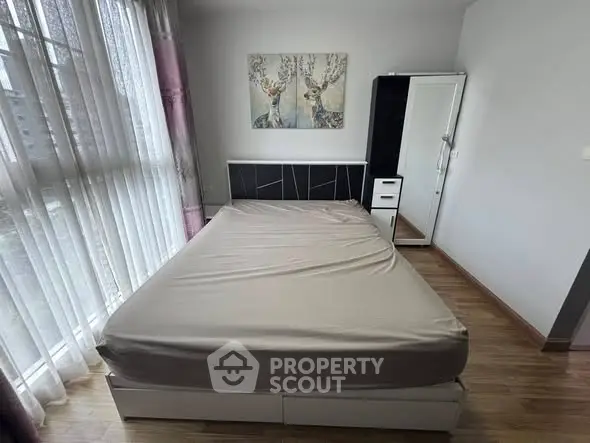 Cozy bedroom with large window and modern decor, perfect for relaxation.