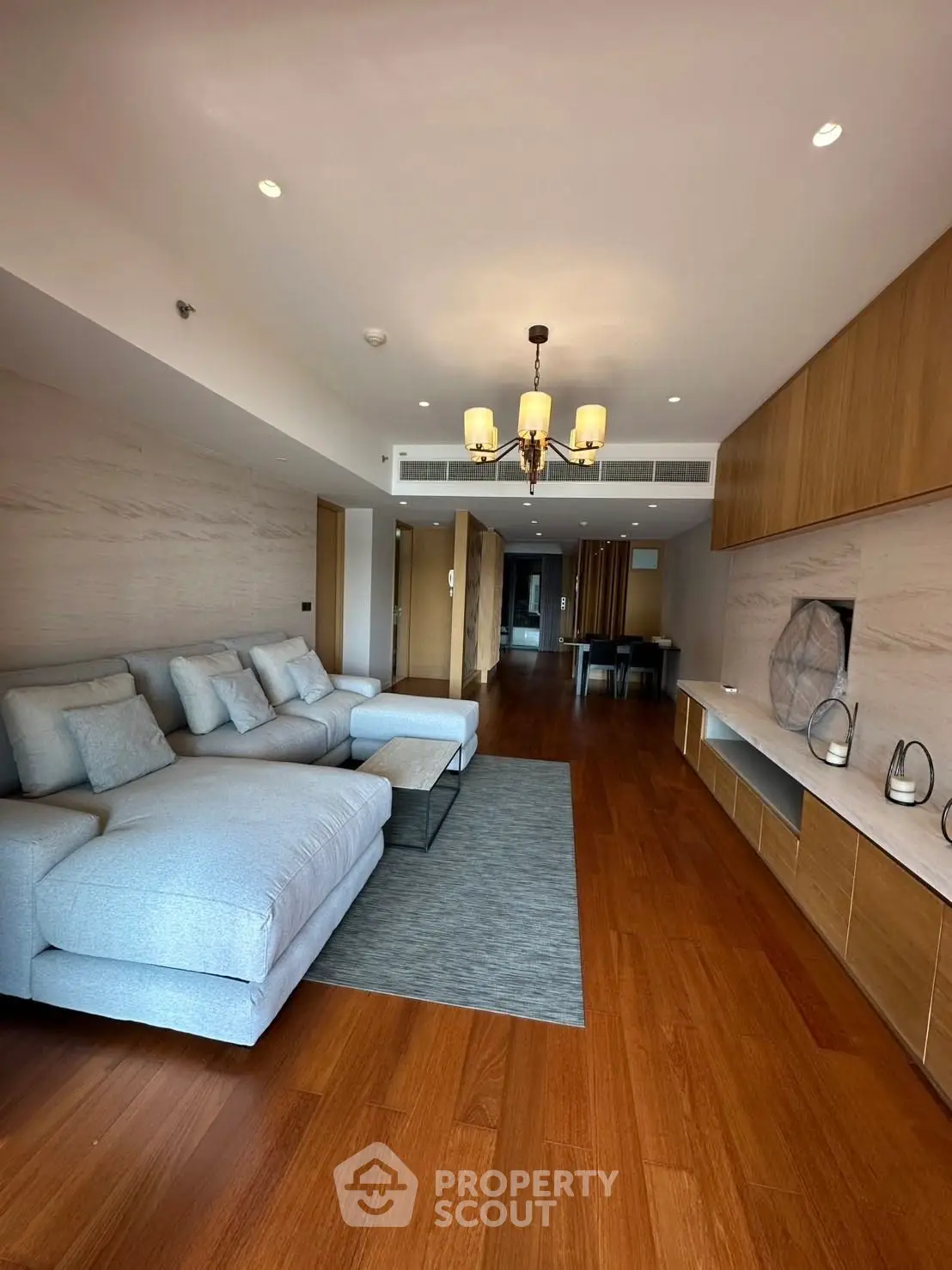 Spacious modern living room with elegant wooden flooring and cozy sectional sofa.