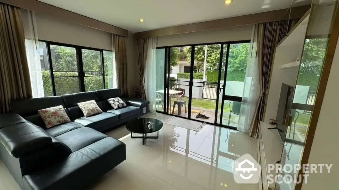 Spacious living room with gleaming floors, plush sectional sofa, and floor-to-ceiling windows leading to a serene balcony view.