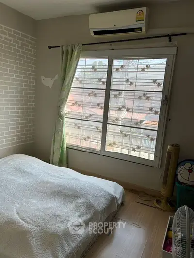 Cozy bedroom with air conditioning and large window offering natural light.