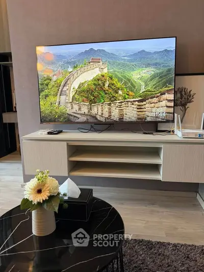 Modern living room with large TV and stylish decor, perfect for relaxation and entertainment.