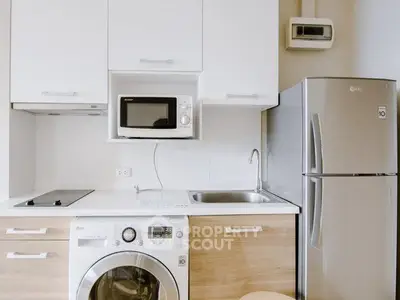 Modern kitchen with sleek appliances including fridge, washing machine, and microwave in a compact layout.
