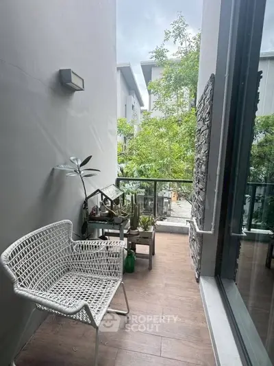 Charming balcony with modern seating and lush greenery view, perfect for relaxation and enjoying nature.