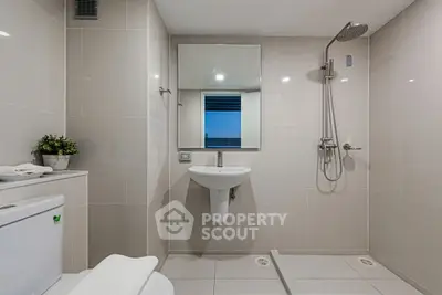 Modern bathroom with sleek fixtures and neutral tiles, featuring a walk-in shower and contemporary design.