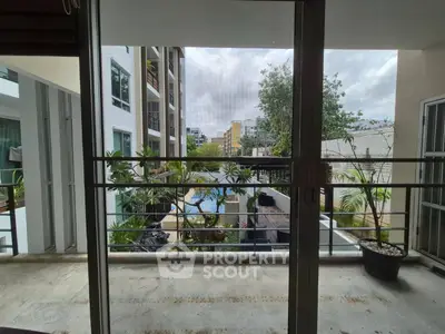 Modern apartment balcony with pool view and lush greenery
