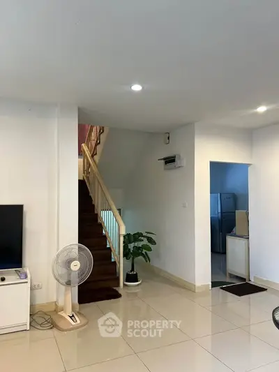 Spacious living area with modern staircase and sleek tile flooring