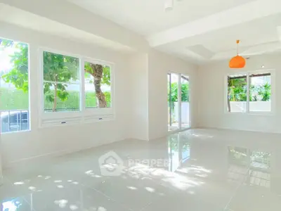 Bright and spacious living room with large windows and glossy tiled floors, perfect for natural light lovers.