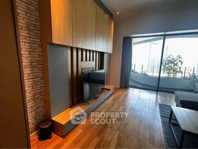 Modern living room with wooden flooring and large TV, featuring a balcony with city view.