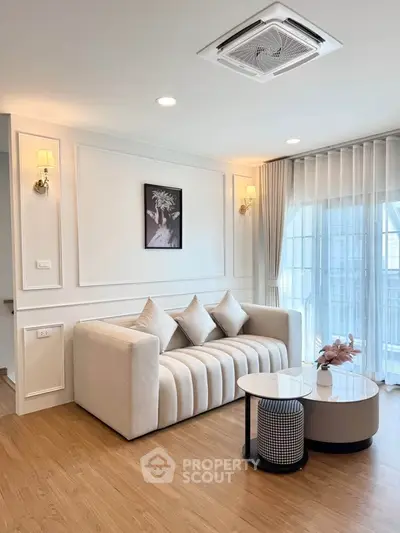Elegant living room with plush sofa, modern decor, and large windows for natural light.